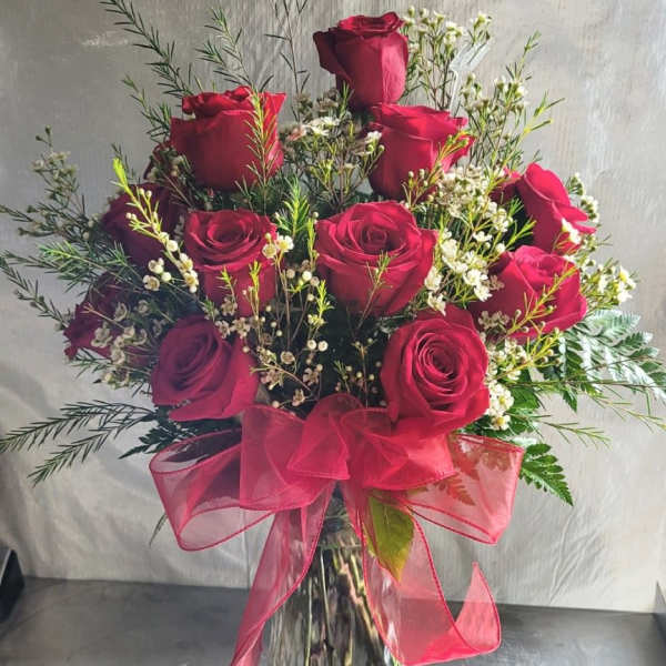 Red roses in a clear glass vase with a pink ribbon