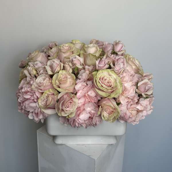 Pink roses and carnations arranged in a white rectangular vase