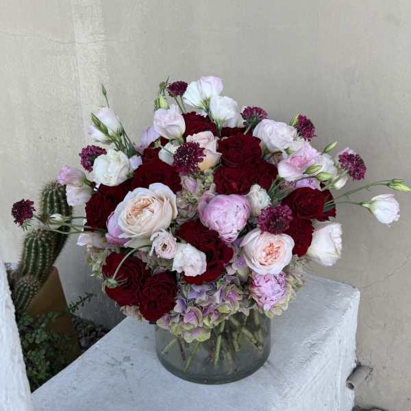 Bouquet of red and blush roses with pale lisianthus in a glass vase