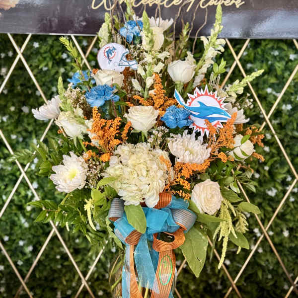 Tall bouquet of white and blue flowers in a glass vase with ribbon