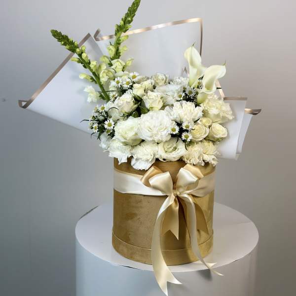 White floral bouquet in a gold hatbox with a satin bow