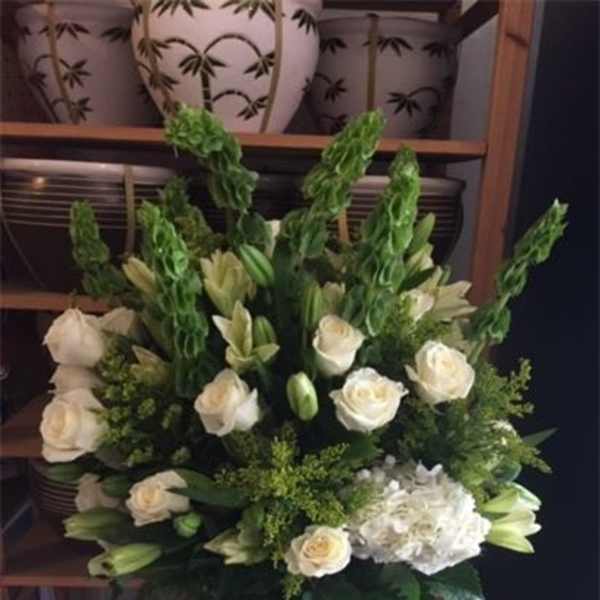 White roses and lilies in a tall vase arrangement
