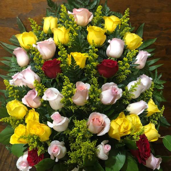Tiered bouquet of yellow, pink, and red roses with greenery