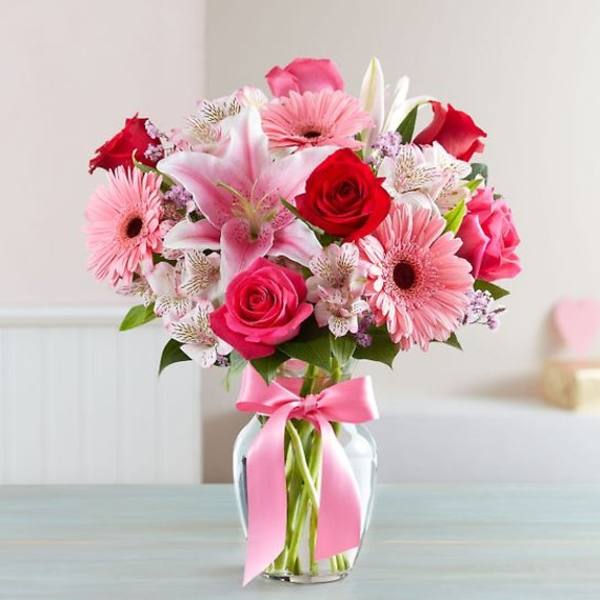 Pink and red mixed bouquet in a glass vase with a pink ribbon