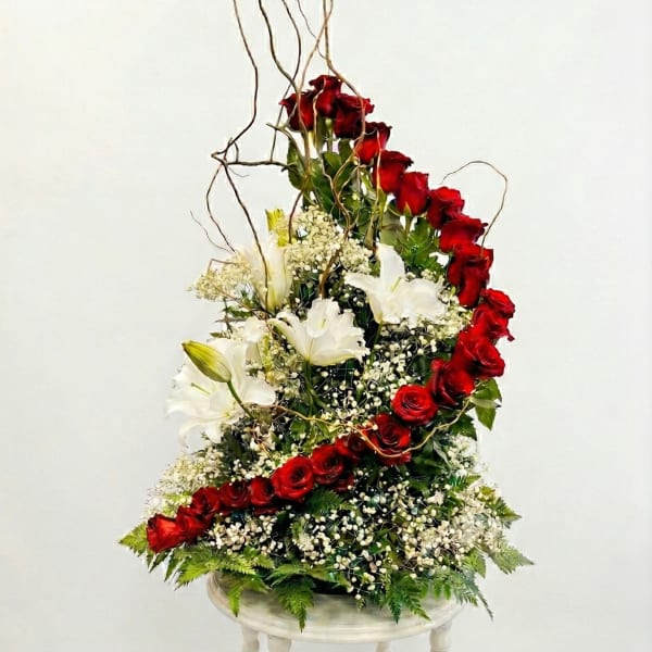 Tall arrangement of red roses and white lilies on a pedestal stand