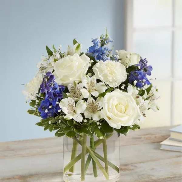 White and blue bouquet in a clear glass vase