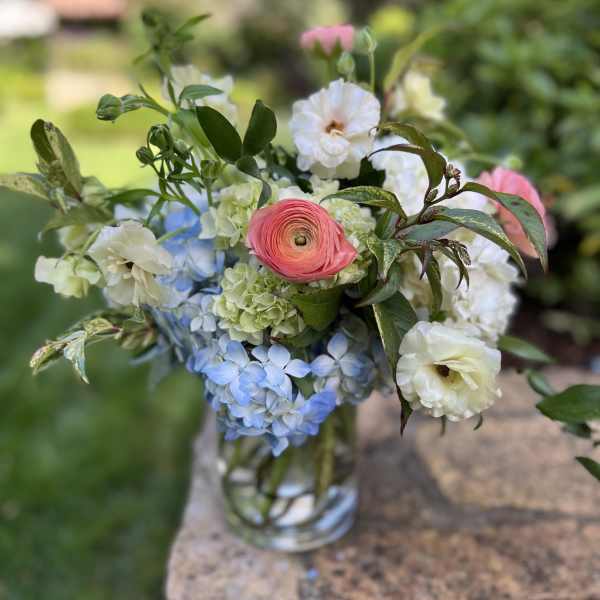 Mixed bouquet in a clear glass vase with pink, white, and blue blooms