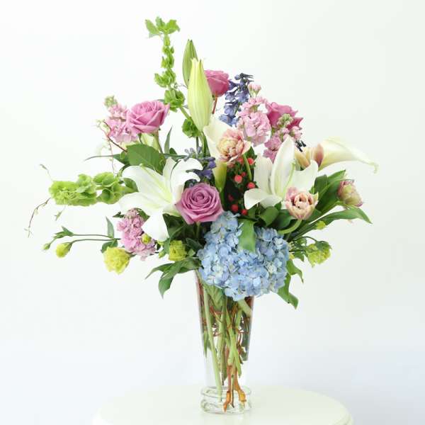 Mixed bouquet with lilies, roses, and hydrangeas in a clear glass vase