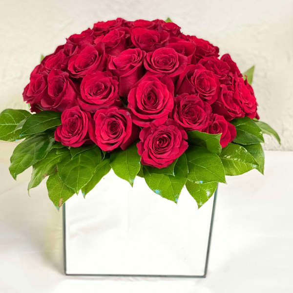 Red rose arrangement in a white square vase