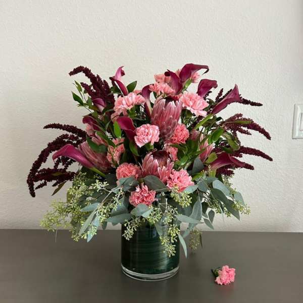 Pink and burgundy floral arrangement in a glass vase