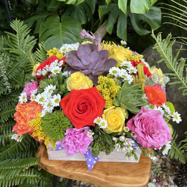 Colorful bouquet with roses, daisies, and succulents in a wooden box