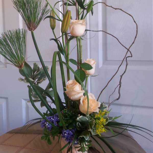 Tall floral arrangement with cream roses and lilies in a white vase