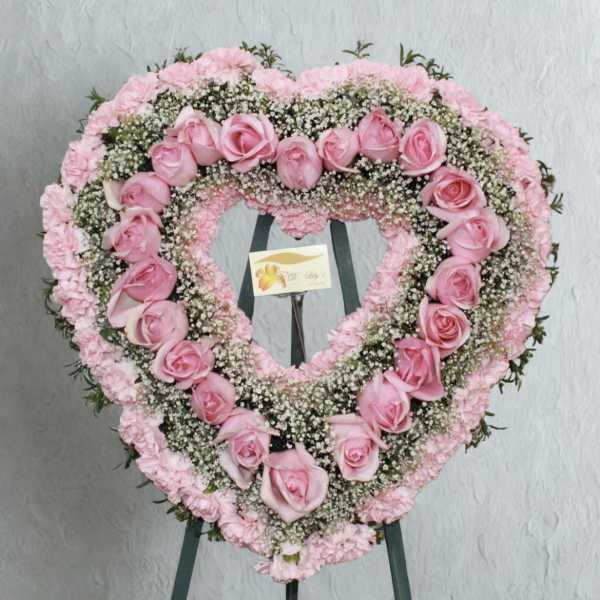 Heart-shaped pink rose and carnation floral wreath on an easel