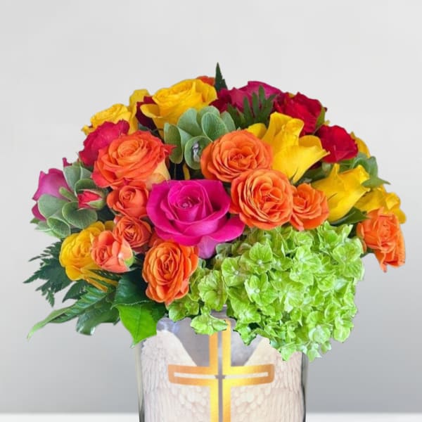 Bright mixed rose bouquet in a glass vase with a cross design