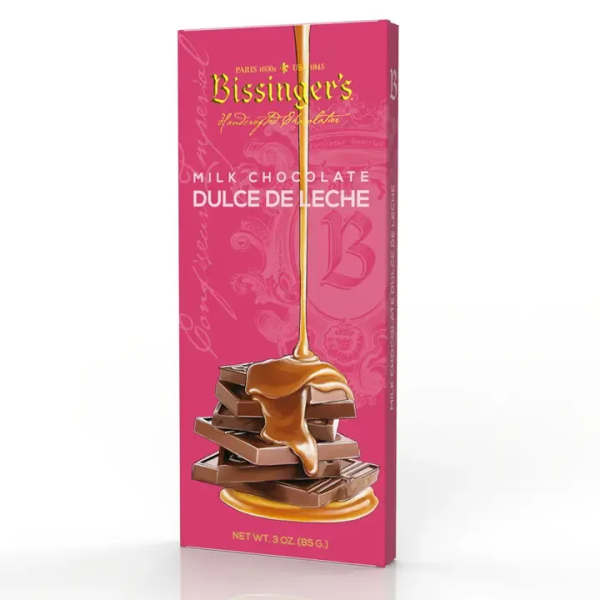 Pink boxed milk chocolate dulce de leche bar with caramel pouring over stacked chocolate pieces