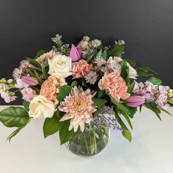 Pastel bouquet of roses, carnations, and chrysanthemums in a clear glass vase