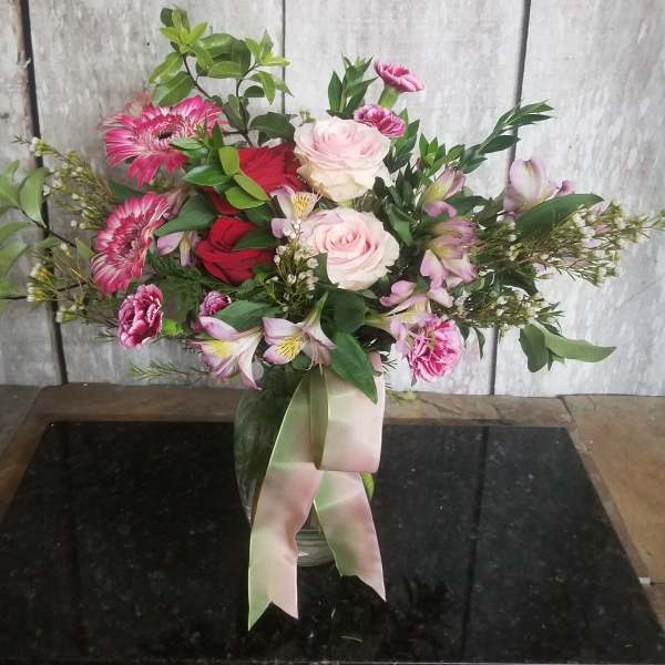 Mixed pink and red bouquet in a glass vase with a ribbon