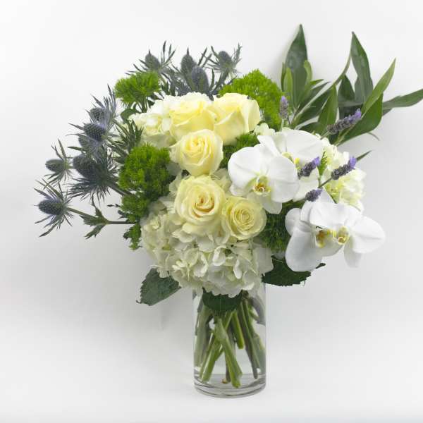 White roses and orchids in a clear glass vase