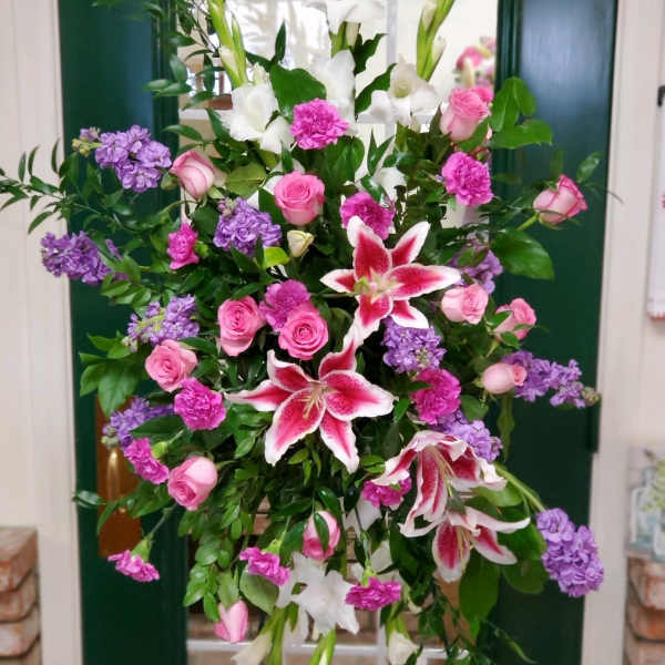 Tall floral spray with pink roses, white lilies, and purple blooms