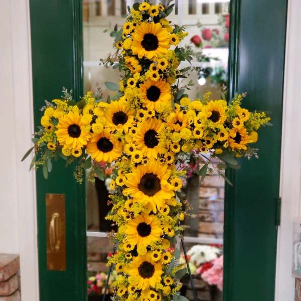 Yellow sunflower cross arrangement on a stand