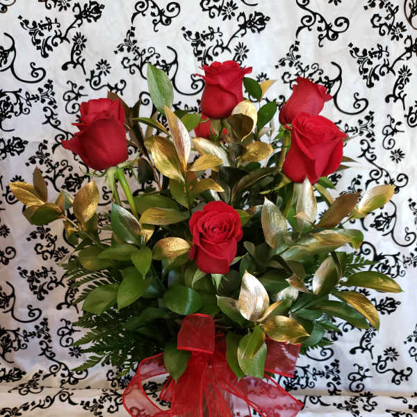 Red roses arranged in a clear glass vase with a red ribbon