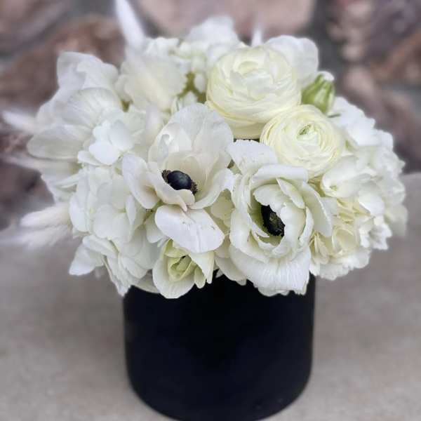 White floral bouquet in a black cylindrical vase