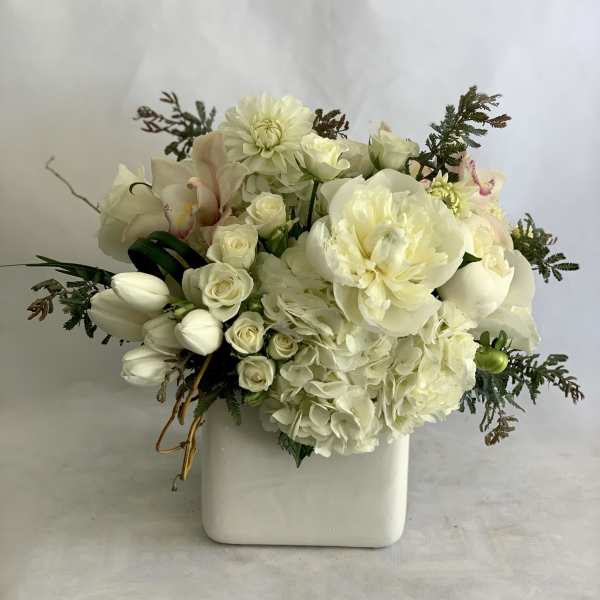 White floral arrangement in a square ceramic vase
