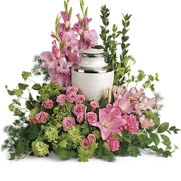 Pink and green floral urn arrangement with lilies, roses, and carnations around a white cremation urn
