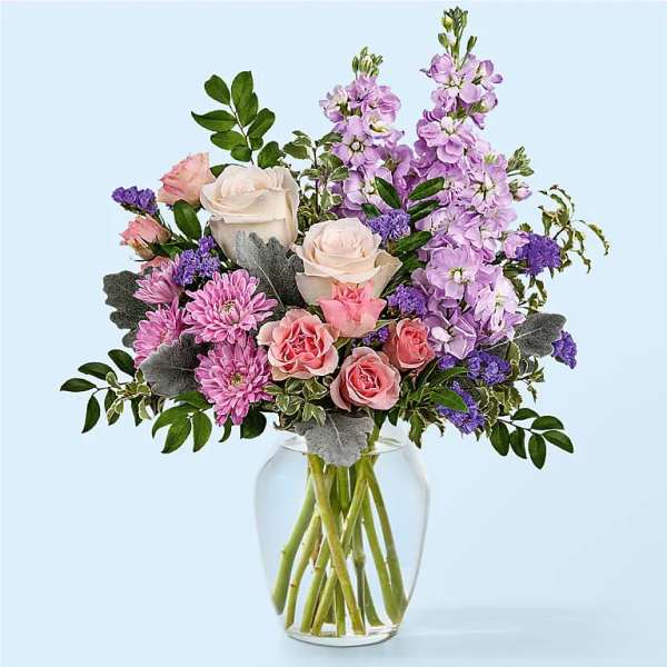 Mixed bouquet of pink and lavender flowers with white roses in a clear glass vase
