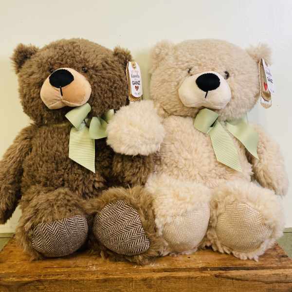 Two plush teddy bears with green ribbons sitting side by side