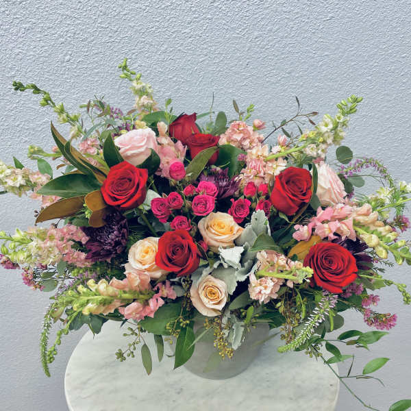 Mixed bouquet of red and blush roses in a clear vase