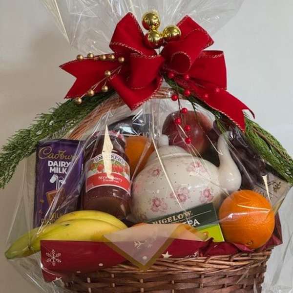 Gift basket with fruit, tea, chocolate, and a teapot wrapped in clear cellophane