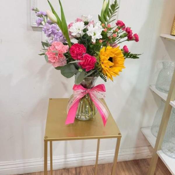 Mixed bouquet in a glass vase with a pink ribbon