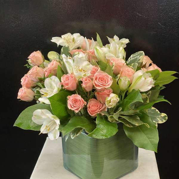 Pink roses and white alstroemeria arranged in a green glass vase
