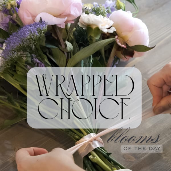 Wrapped bouquet of pale pink and lavender flowers tied with a satin ribbon