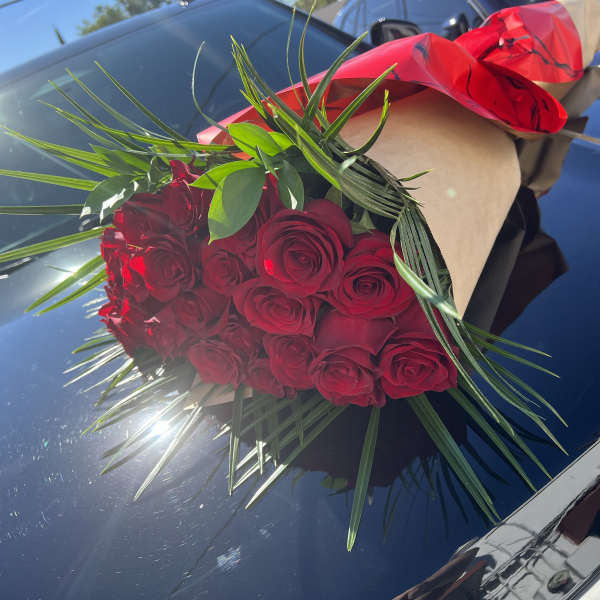 Bouquet of red roses wrapped in brown paper with red ribbon