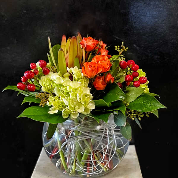 Orange roses and pale hydrangeas in a clear glass vase