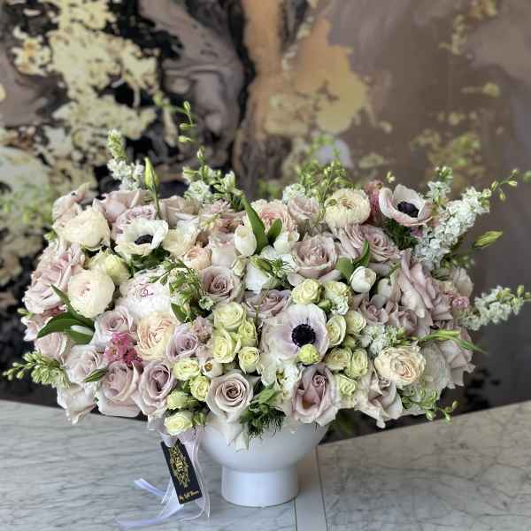 Large pastel bouquet of roses and anemones in a white vase