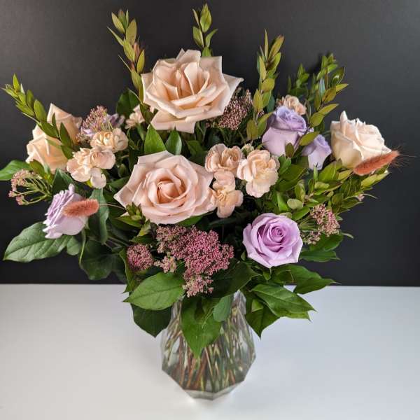 Bouquet of blush and lavender roses in a clear glass vase
