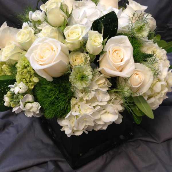 White roses and hydrangeas arranged in a black vase