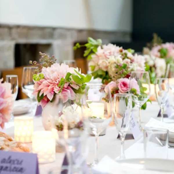 Pink floral centerpieces on a set dining table with candles and glassware