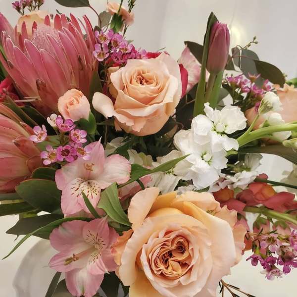 Bouquet of peach roses, pink protea, and white flowers