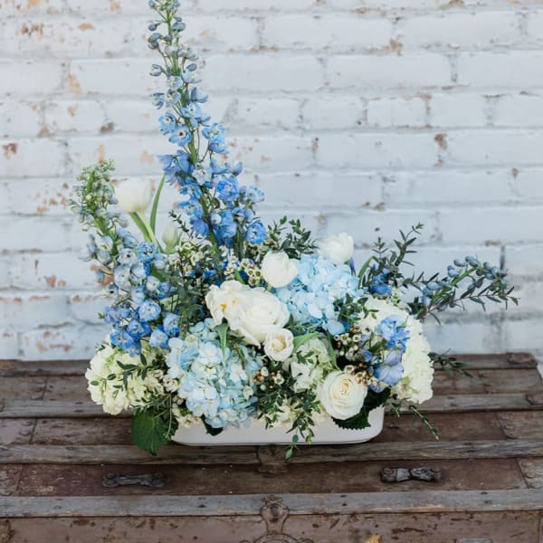 Blue and white floral arrangement in a low white container