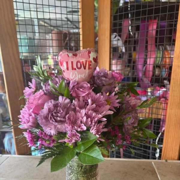 Pink and purple bouquet in a clear vase with an "I Love You" balloon