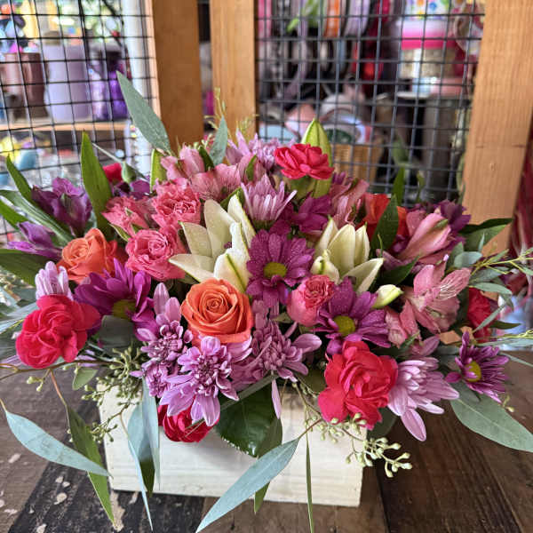 Mixed pink and purple bouquet with roses and daisies in a white box