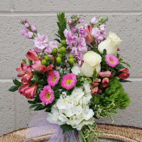 Mixed pink and white bouquet in a glass vase with a lavender ribbon