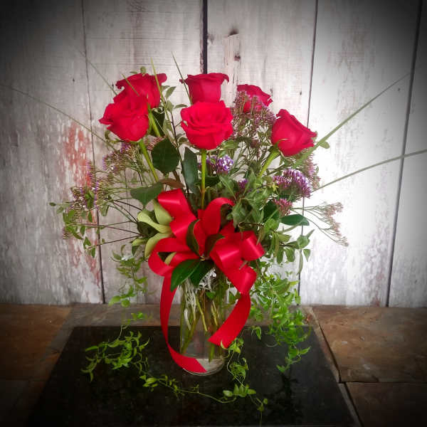 Bouquet of red roses in a clear glass vase with a red ribbon