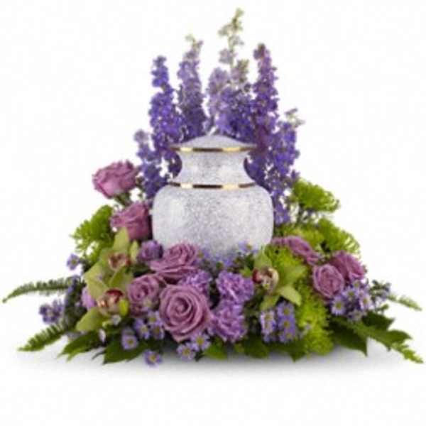 Cremation urn surrounded by lavender and purple flowers with taller blooms rising behind.