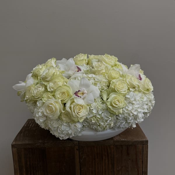 White and pale yellow floral arrangement in a low white bowl