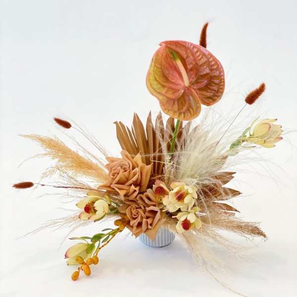 Arrangement with peach flowers and dried grasses in a small vase